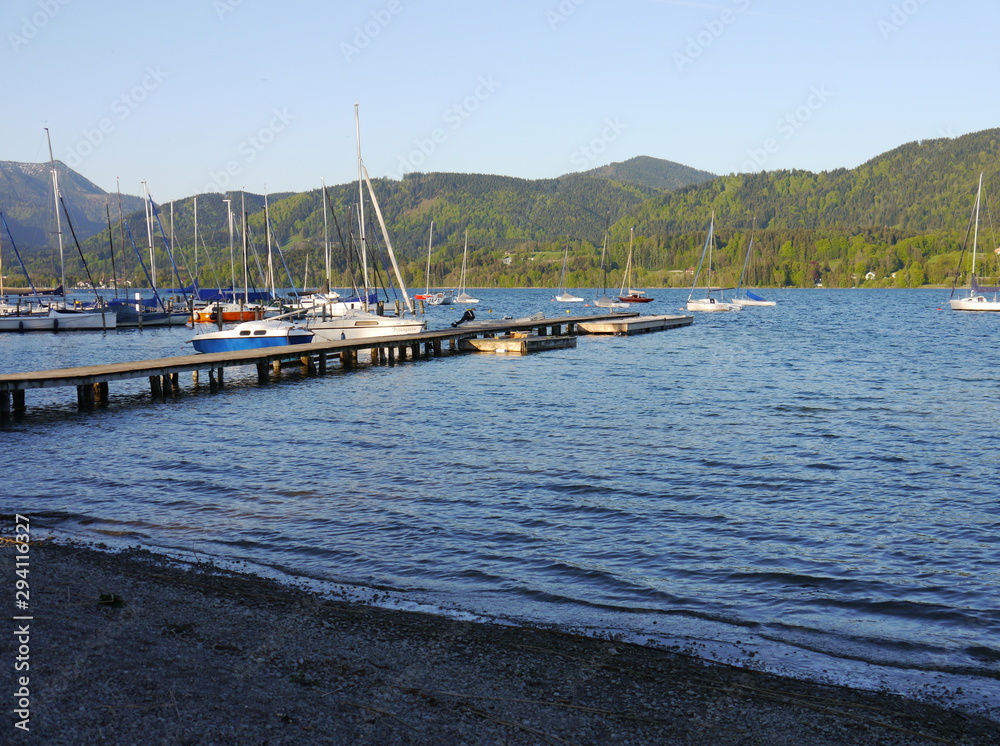 lake in the mountains and sailboats in harbor on a beautiful sunny summer day with blue sky
