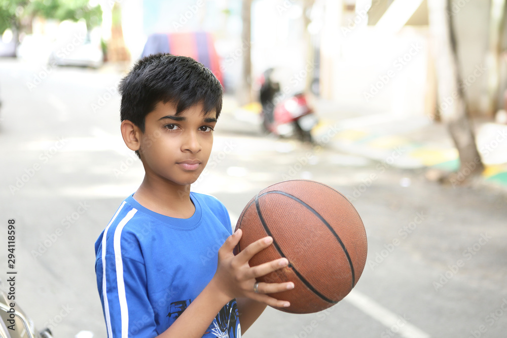 Fototapeta premium Portrait of Indian boy holding basketball