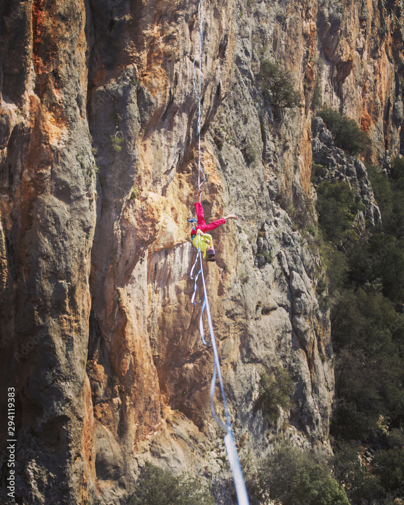 Obraz premium A woman is walking along a stretched sling. Highline in the mountains. Woman catches balance. Performance of a tightrope walker in nature.