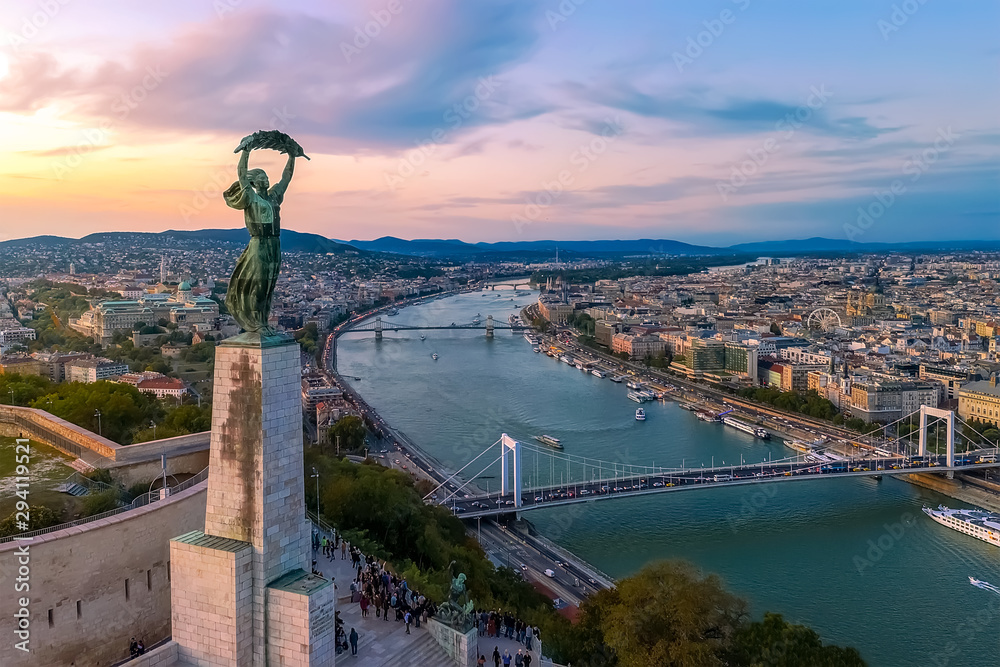 Naklejka premium Pejzaże miejskie Budapesztu tworzą wzgórze Gellerta. Niesamowity zachód słońca w tle. Obejmował Dunaj, historyczne mosty, Dwontown Budapesztu,