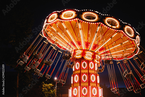 Foto Illuminated swing chain carousel in amusement park at the night