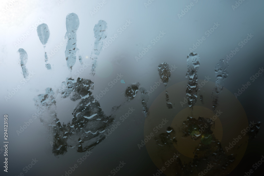 handprints on foggy glass with raindrops
