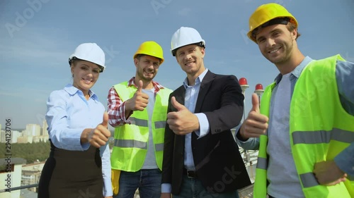 Professional construction team showing thumbs up gesture smiling on camera
