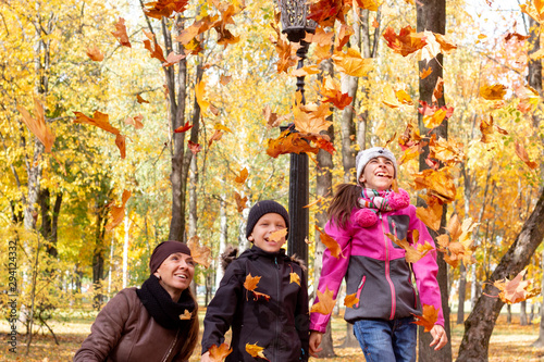 happy family playing with fallen leaves in autumn park