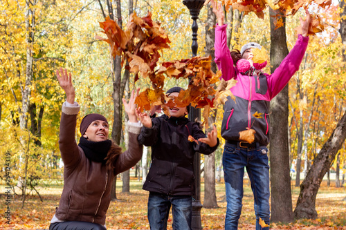 happy family playing with fallen leaves in autumn park