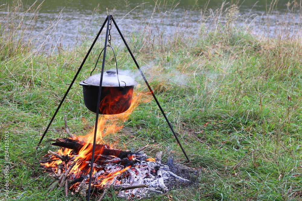 cooking delicious tasty food outdoors on fire in iron pot in summer in good weather with wood from forest cooking delicious tasty food outdoors on fire in iron pot in summer in good weather with wood from forest