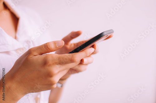 A close-up view of a young woman holding a smartphone on a white background