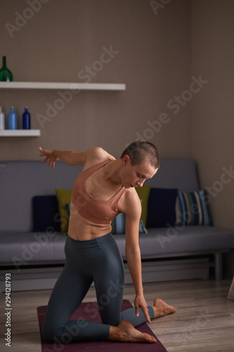 Fit caucasian woman sitting on mat and stretch muscles of body. Female practicing fitness exercises at home
