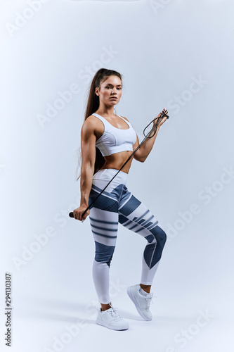 strong lovely sportswoman holding skipping rope and posing to the camera, full length photo. isolated white background
