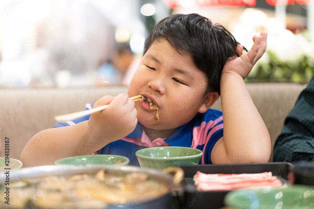 A kid is eating deliciously boiled beef with sukiyaki soup in a shabu pot at the Japanese restaurant. A kid is eating deliciously boiled beef with sukiyaki soup in a shabu pot at the Japanese restaurant.