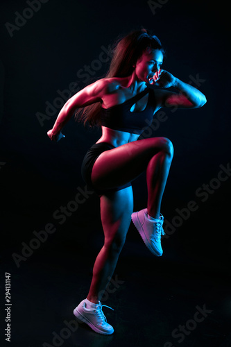 pleasant gorgeous slim well-built woman taking part in fitness program, cross fit, isolated black background, studio shot, full length photo