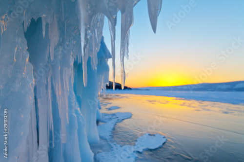Baikal Lake in February at sunset. The icy cliffs of Olkhon island with long icicles. Shallow depth of field, focus on icicle