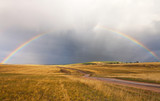 Lake Baikal. Olkhon Island in September. Rainbow arch after rain over a dirt road leading to Cape Khoboy