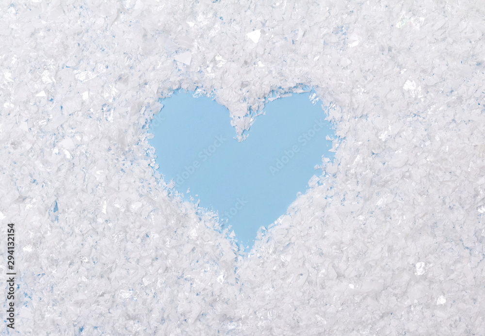 White fluffy artificial snow on blue background with heart White fluffy artificial snow on blue background with heart