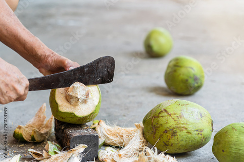 Green fresh coconut peeling and shelling with heavy chop knife for juice.