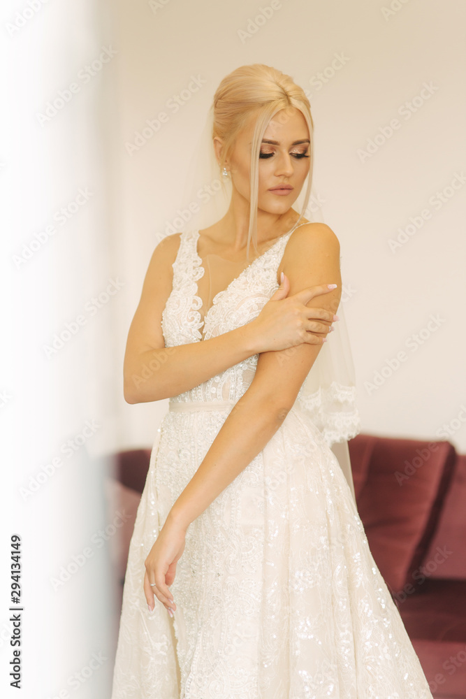 Young and beautiful bride at home. Blond hair girl in wedding dress Young and beautiful bride at home. Blond hair girl in wedding dress