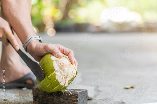 Green fresh coconut peeling and shelling with heavy chop knife for juice.