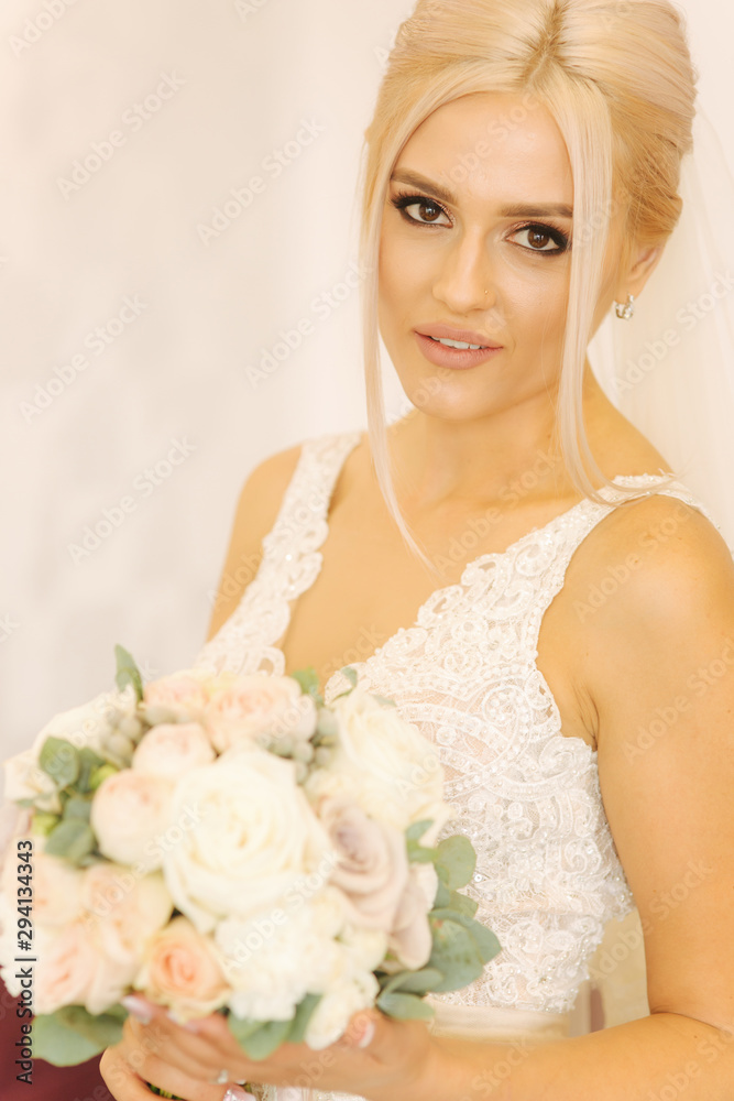 Naklejka premium Portrait of gorgeous bride at home. Charming woman with bouquet. Morning of beautiful bride. Wedding day