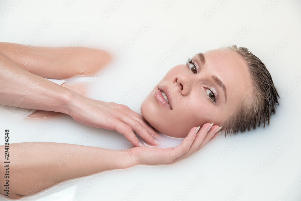 Portrait of a beautiful blonde girl in milk in the bathroom top view. Spa and skincare concept Portrait of a beautiful blonde girl in milk in the bathroom top view. Spa and skincare concept