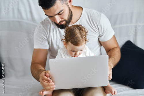 beautiful lovely nice little girl sitting on the knees of her daddy and typing something. close up photo. education