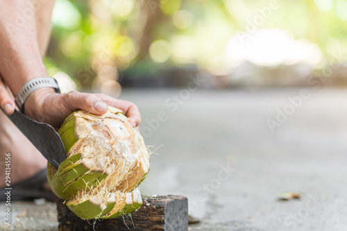 Green fresh coconut peeling and shelling with heavy chop knife for juice.