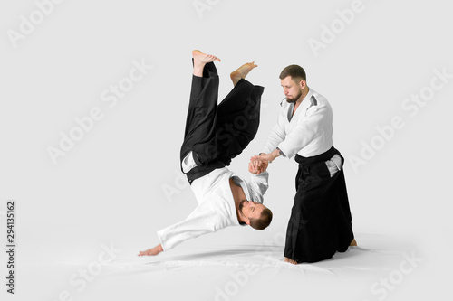 Two caucasian men are practicing aikido on the tatami (isolation path included)