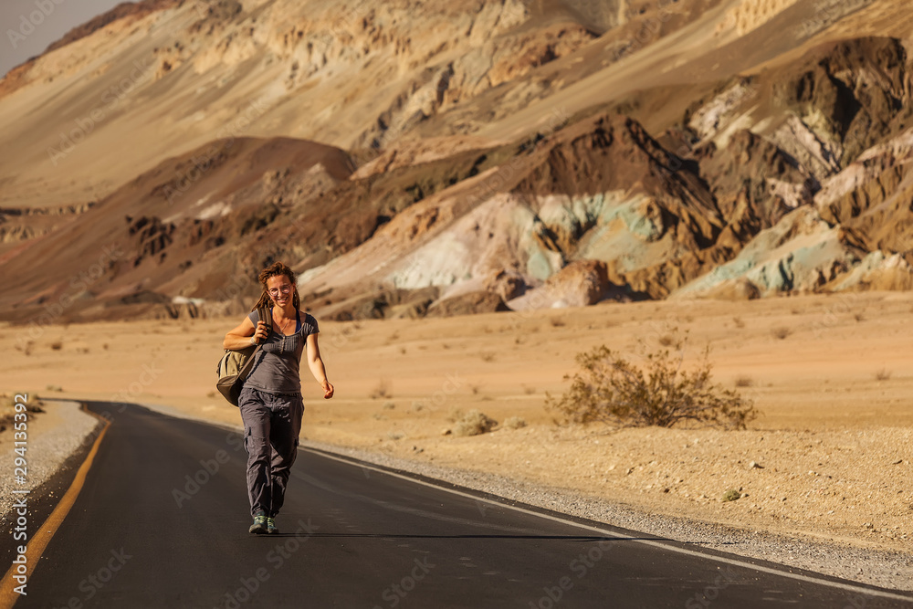 hitchhiker woman walking on a road in USA