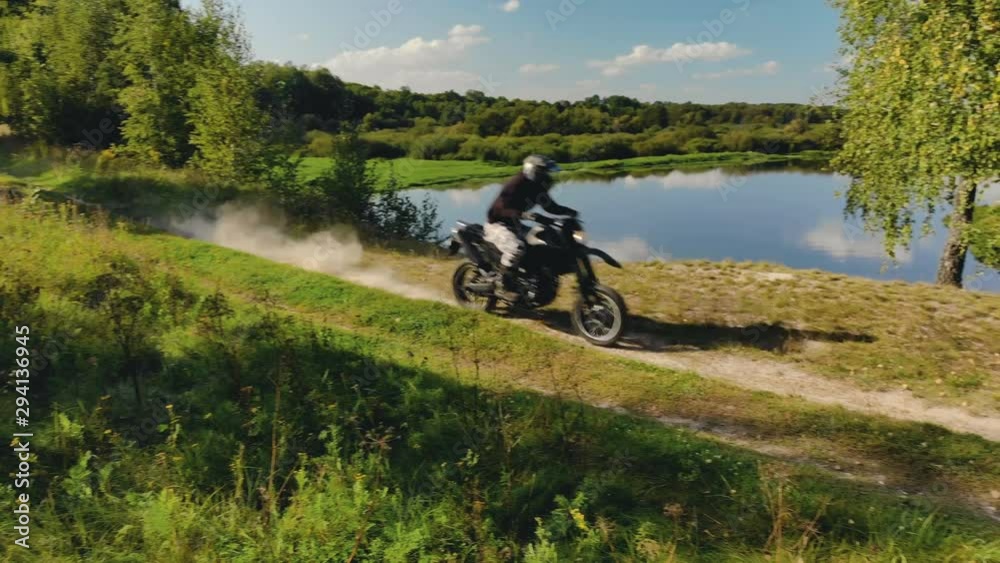 Motorcyclist in protective gear on black Enduro, motard, extreme riding near the cliff above the river in good Sunny weather Motorcyclist in protective gear on black Enduro, motard, extreme riding near the cliff above the river in good Sunny weather