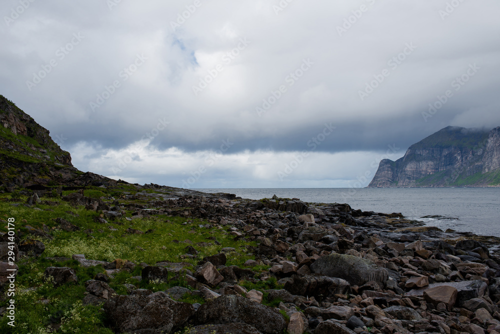 Beautiful nature landscape in North. Scenic outdoors view. Ocean with waves and mountains. Big dark stones. Dramatic storm clouds. Extreme weather, rain and wind. Explore Norway, summer adventure Beautiful nature landscape in North. Scenic outdoors view. Ocean with waves and mountains. Big dark stones. Dramatic storm clouds. Extreme weather, rain and wind. Explore Norway, summer adventure
