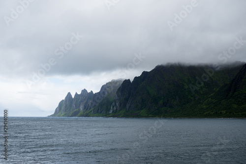 Beautiful nature landscape in North. Scenic outdoors view. Ocean with waves and mountains. Big dark stones. Dramatic storm clouds. Extreme weather, rain and wind. Explore Norway, summer adventure © Iuliia Pilipeichenko