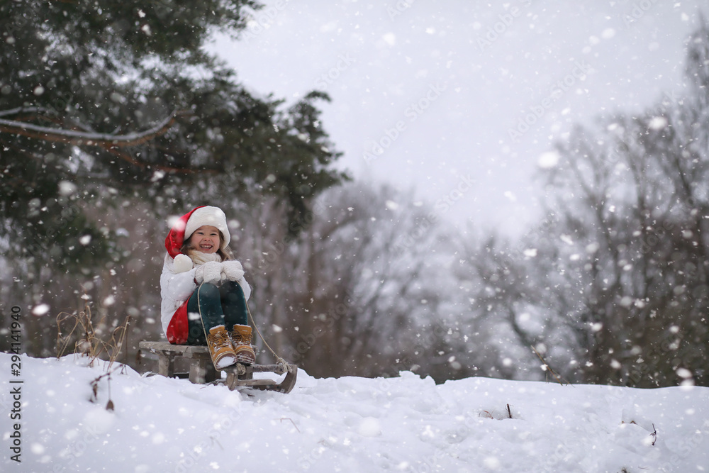 A winter fairy tale,in the forest. A girl on a sled with gifts on the eve of the new year in the park. Two sisters walk in a New Year's park and ride a sled with gifts.