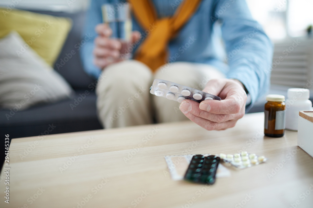 Close up of unrecognizable senior man holding pills and medication, focus on foreground, copy space