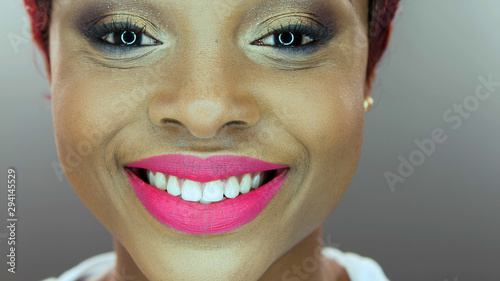 Close-up detail of an African American woman smiling over gray background