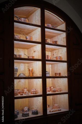 copper and brass antique dishes in a cabinet with lighting