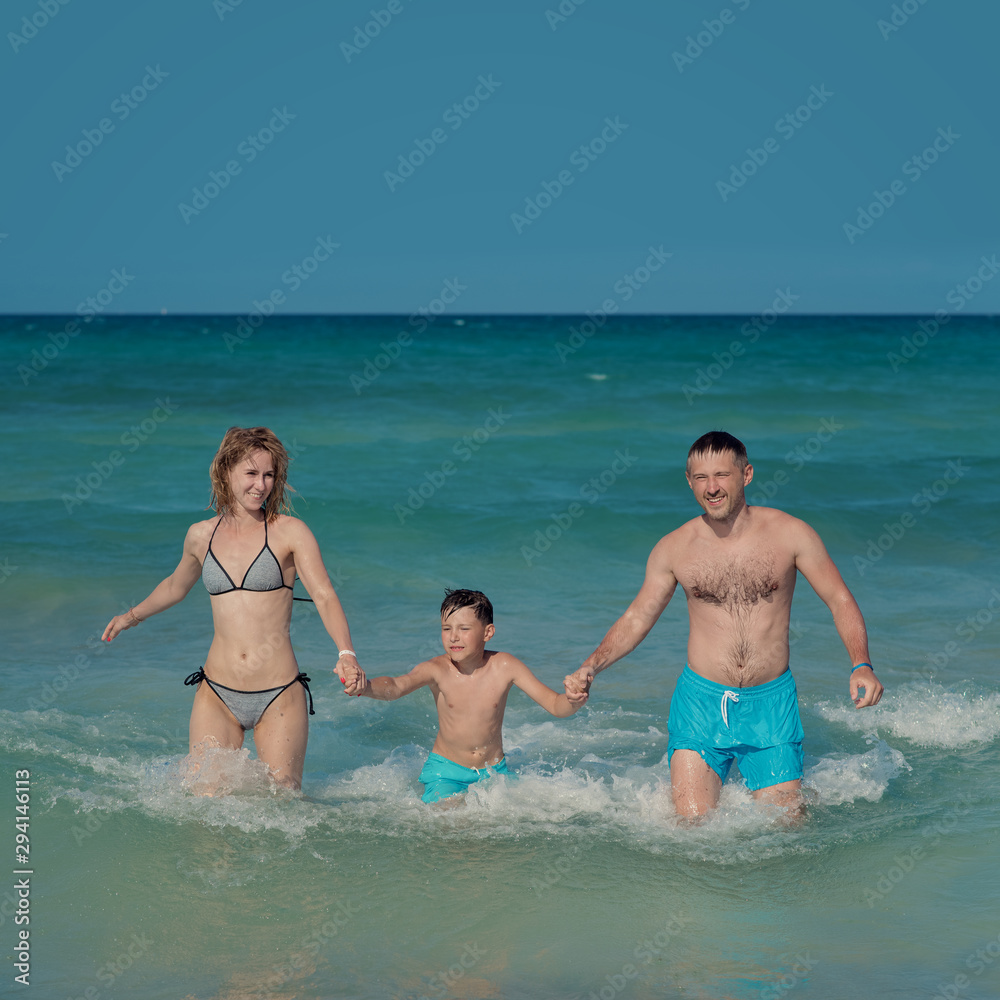 Mom father and son getting out from the sea water. Front view. Mom father and son getting out from the sea water. Front view.