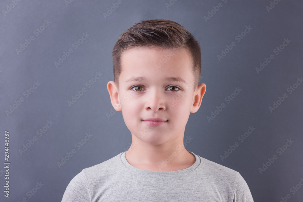 Handsome brunette boy smile and look at camera over grey background Handsome brunette boy smile and look at camera over grey background