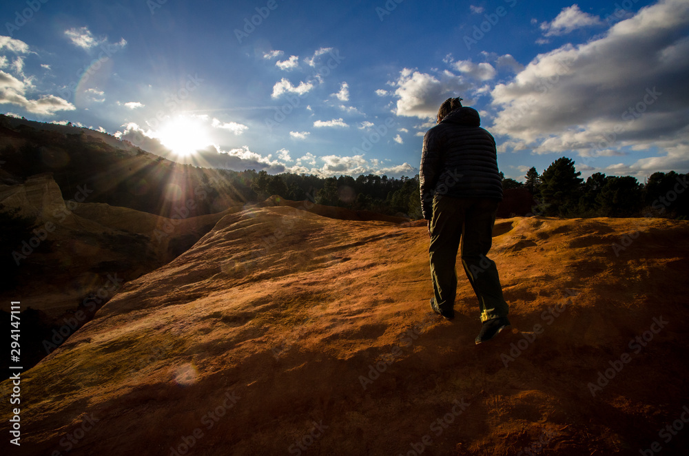 Un homme marchant sur une montagne. Un randonneur sur un rocher. Une randonnée au soleil.