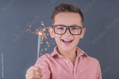 Cheerful brunette boy holding bengal lights  concept of children s emotions and holiday