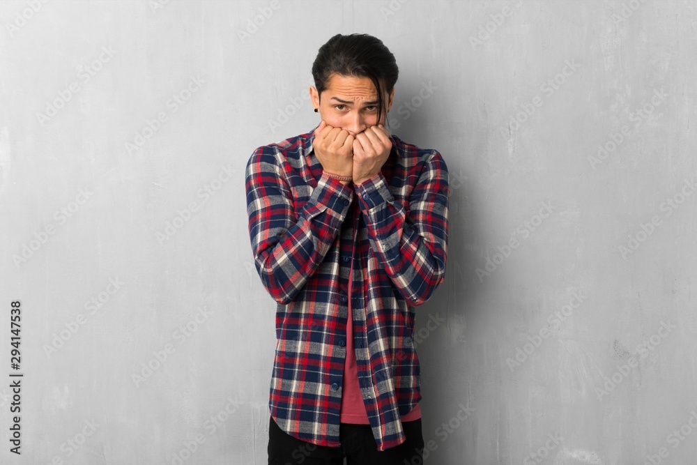 Man over grunge wall is a little bit nervous and scared putting hands to mouth Man over grunge wall is a little bit nervous and scared putting hands to mouth