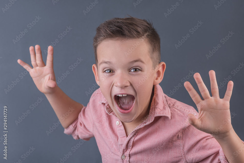 Funny brunette boy is building a frightening face, the concept of children's emotions closeup Funny brunette boy is building a frightening face, the concept of children's emotions closeup