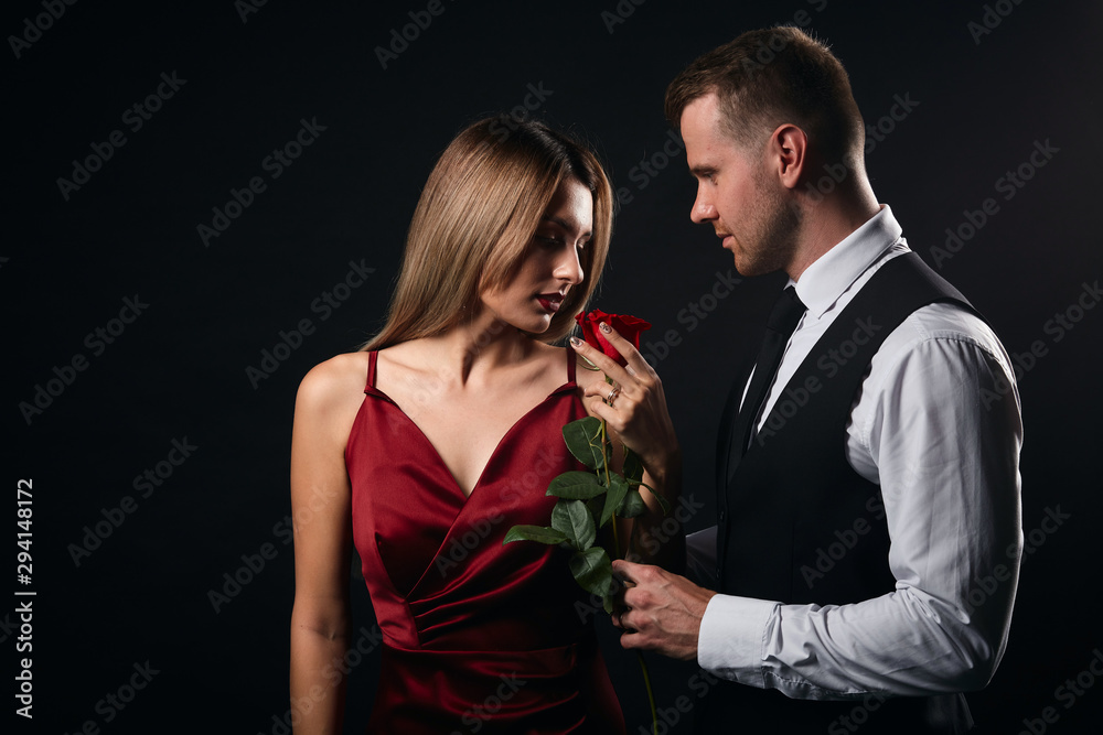 sexy woman enjoying wonderful smell of rose which has been given her by her lover. isolated black background, studio shot