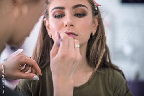 Make-up artist and model in the process of applying make-up  the stage of applying lip gloss
