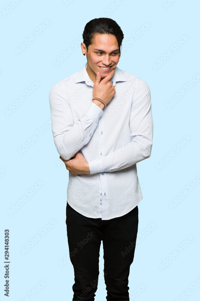 Handsome man looking to the side with the hand on the chin over isolated blue background Handsome man looking to the side with the hand on the chin over isolated blue background