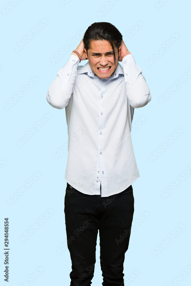 Handsome man takes hands on head because has migraine over isolated blue background Handsome man takes hands on head because has migraine over isolated blue background