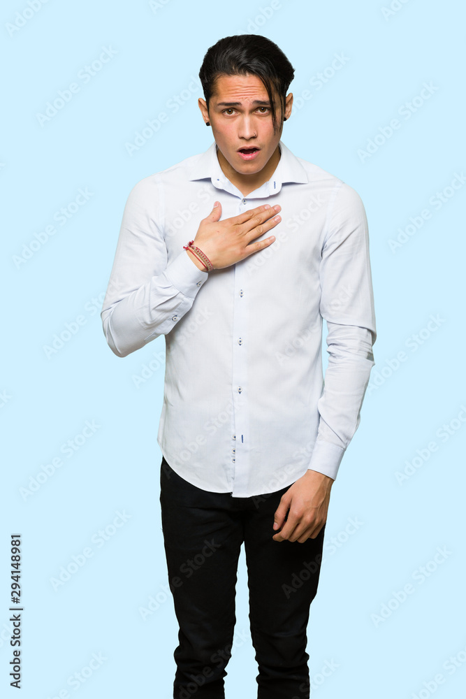 Handsome man surprised and shocked while looking right over isolated blue background
