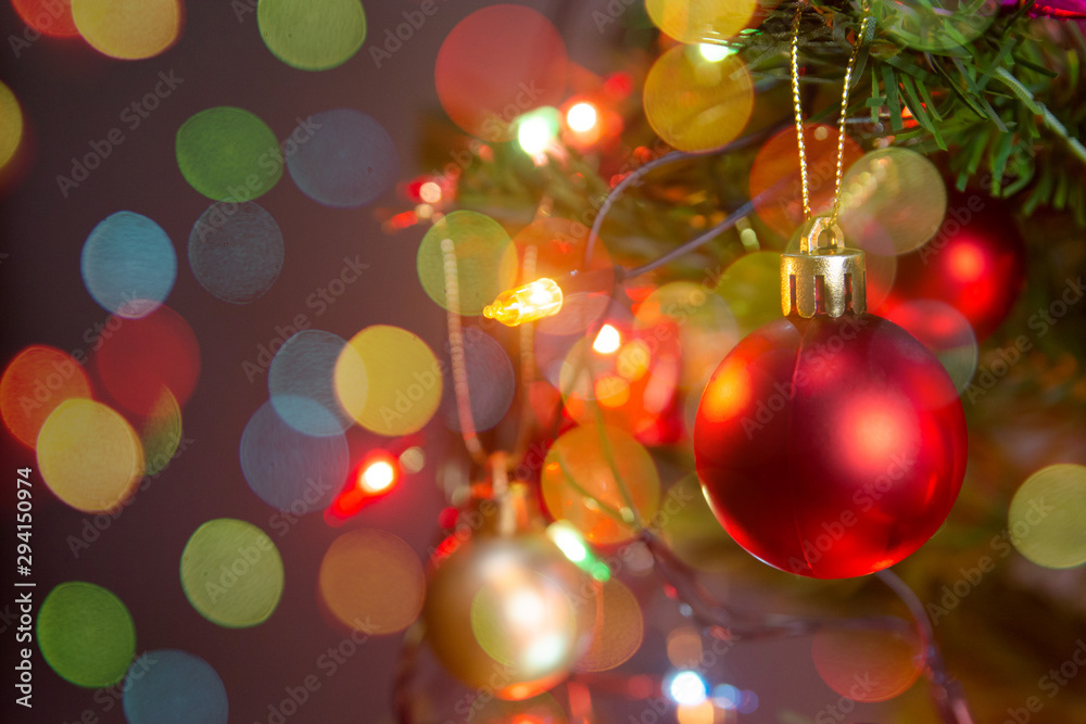 Fototapeta premium Christmas decoration. Hanging red balls on pine branches christmas tree garland and ornaments over abstract bokeh background with copy space.