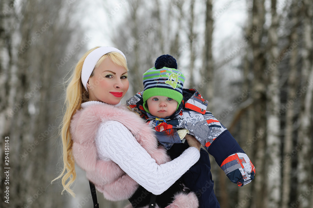 Young mother walks on a winter day with a baby in her arms in the park