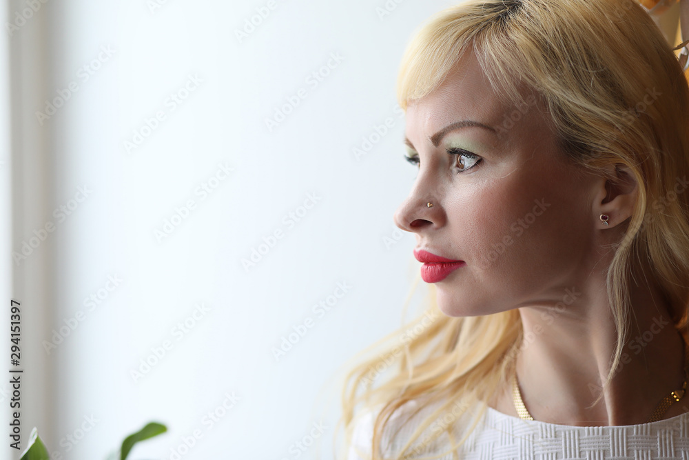 Cute girl is standing by the window looking