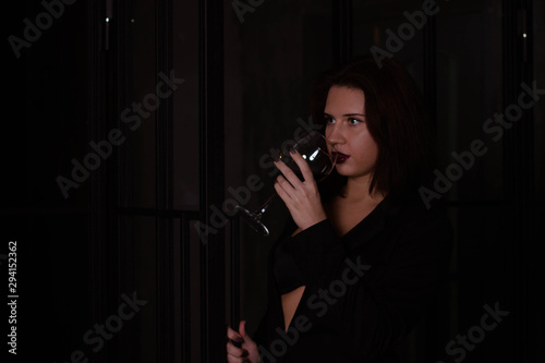 brunette in a black jacket with a glass of red wine