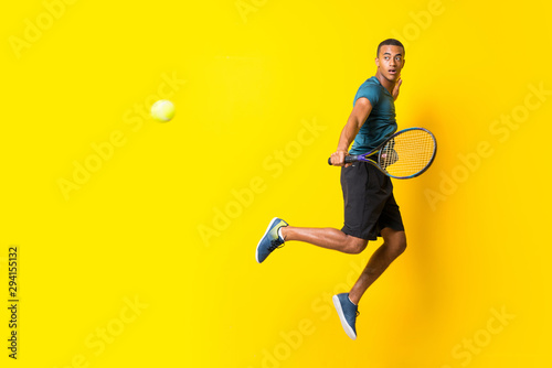 Afro American tennis player man over isolated yellow background © luismolinero